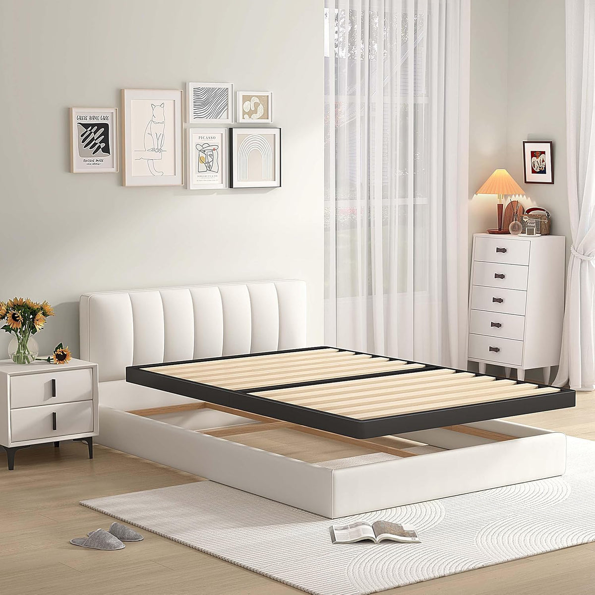 Black metal bed frame with wooden slats shown lifted above a white upholstered bed base in a styled room.