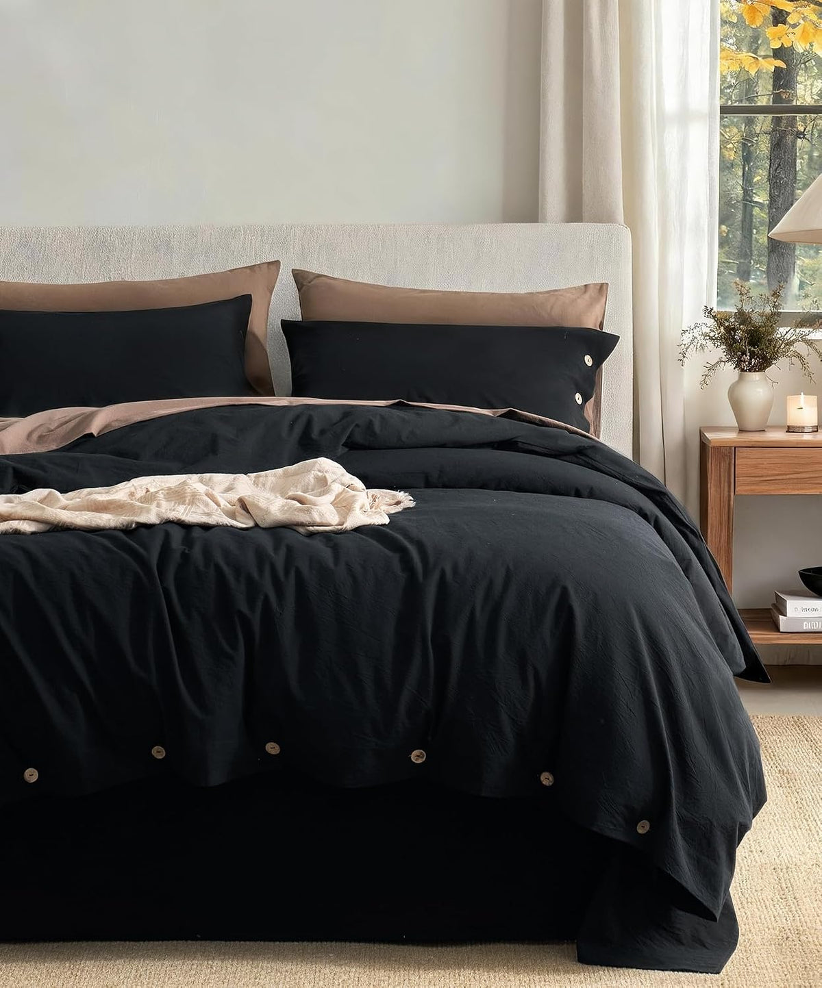 Bedroom front view with black duvet and tan pillow accents on a dressed bed beside a wooden nightstand.