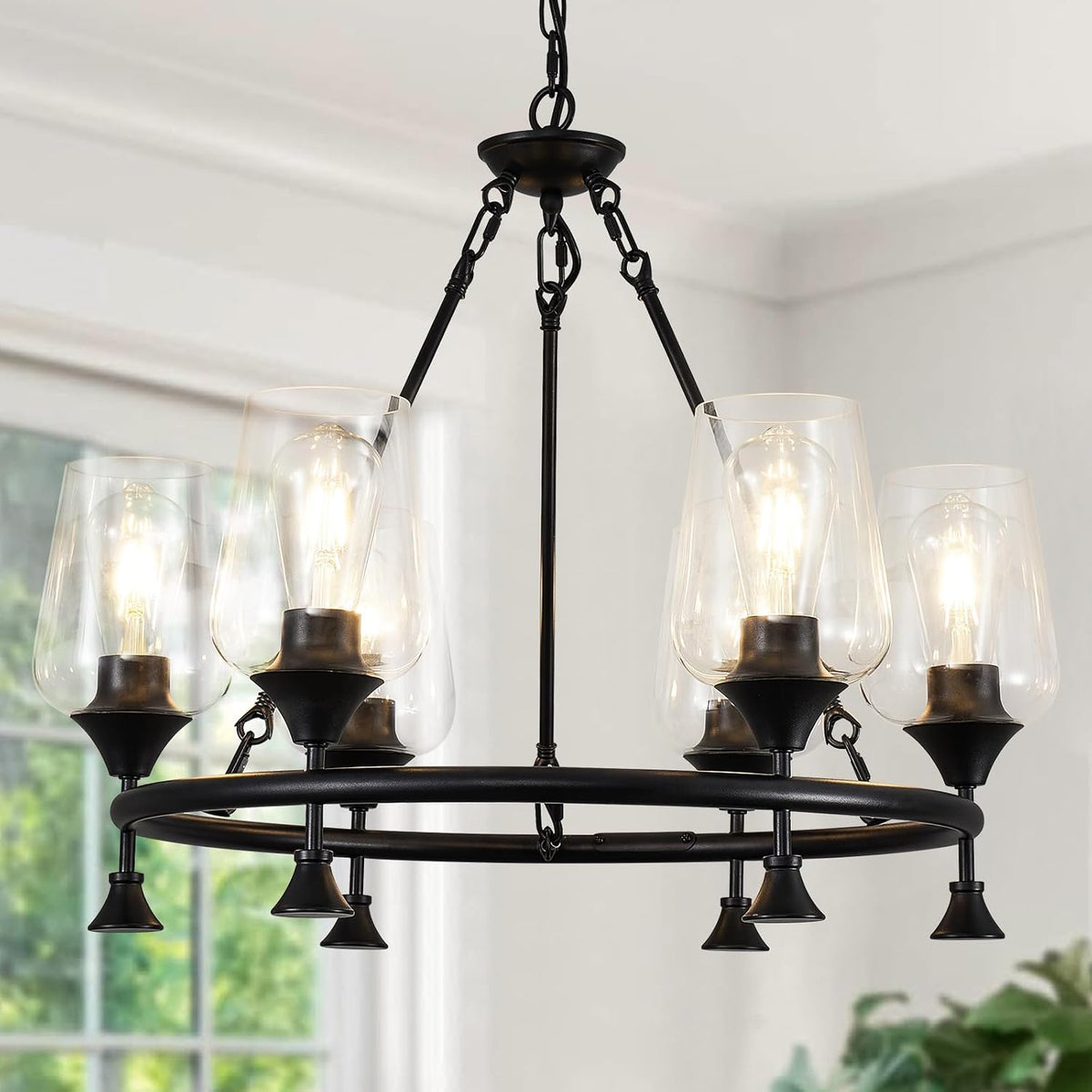 Black circular chandelier with clear glass shades and glowing bulbs, suspended from a chain.