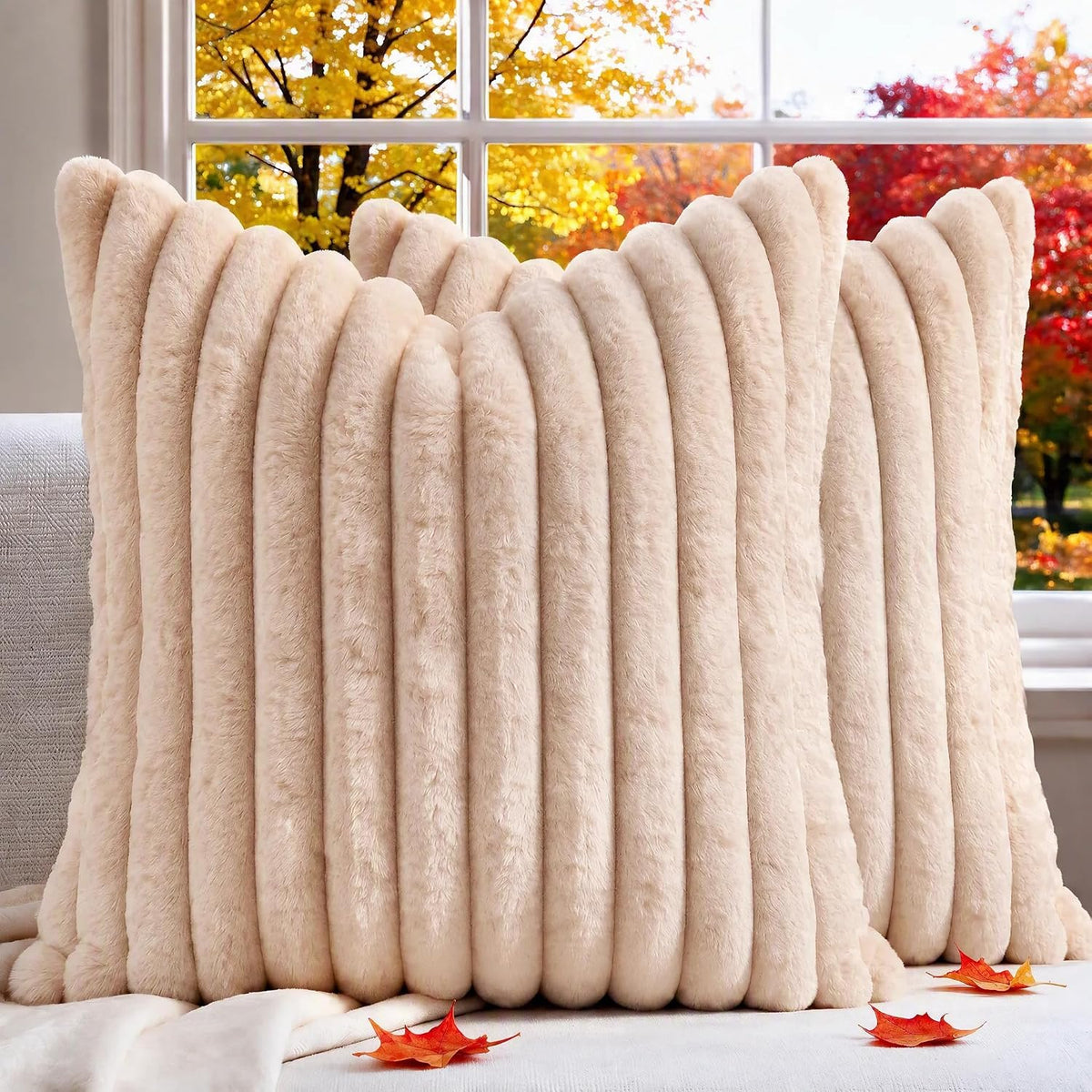 Pair of cream-colored ribbed faux-fur pillow covers with autumn leaves on the surface