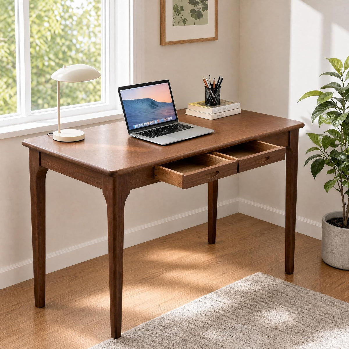 Walnut desk placed by a window with laptop on top and both drawers pulled out