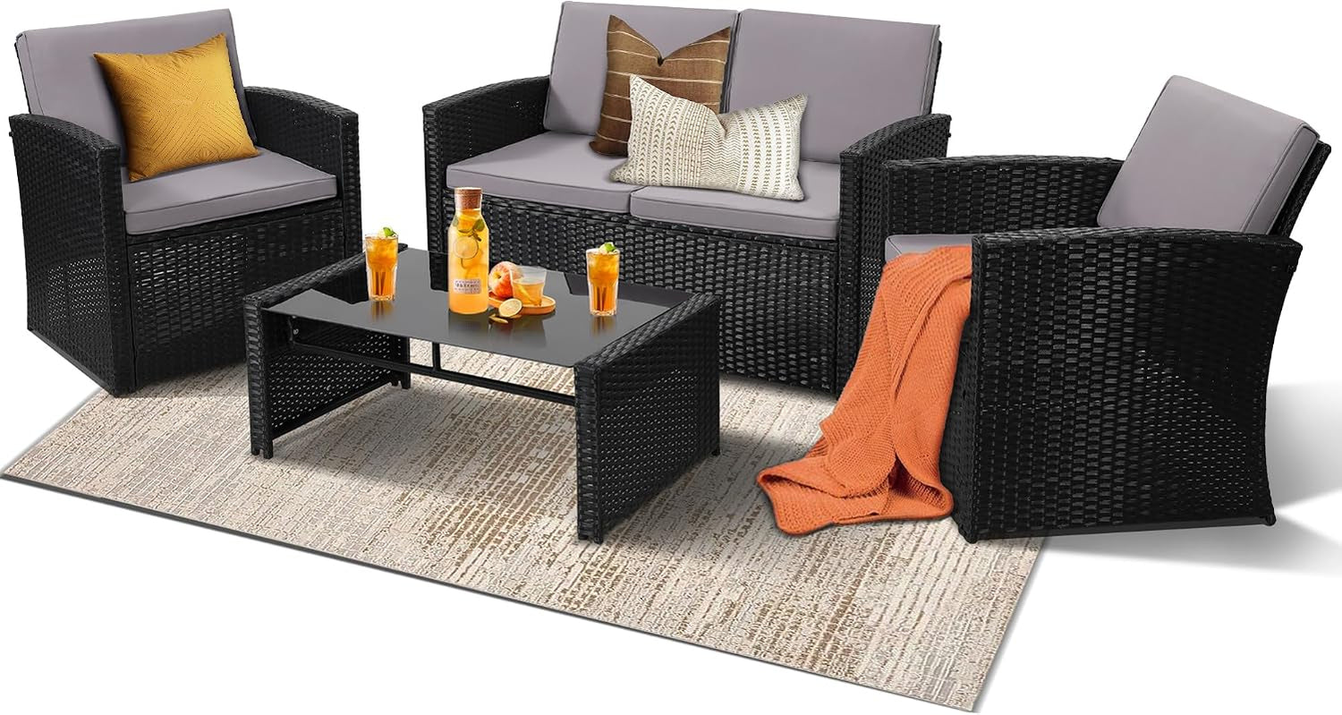 Black wicker loveseat and two chairs with gray cushions and glass-top coffee table, orange throw draped on chair.