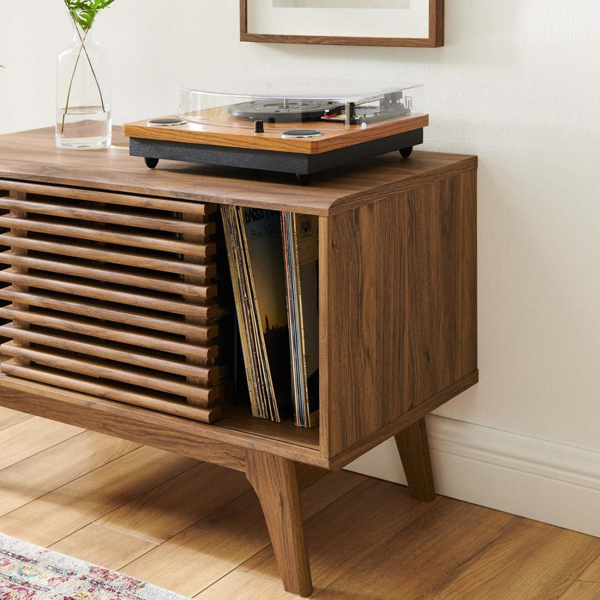 Walnut record stand with a turntable on top and vinyl records stored upright in the open compartment, angled room view.