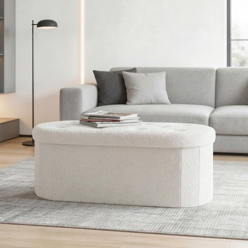White oval storage ottoman with tufted top angled front view in a living room