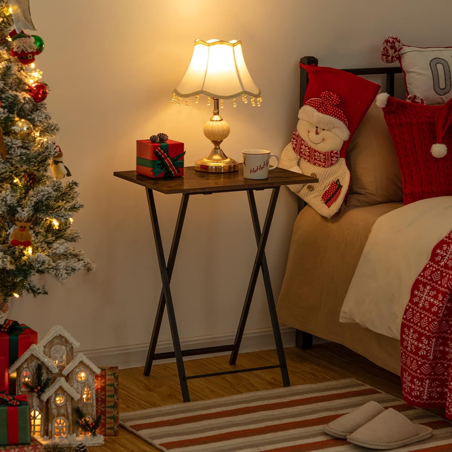 Folding tray table styled as a bedside table with a lamp and holiday decor in a cozy bedroom scene