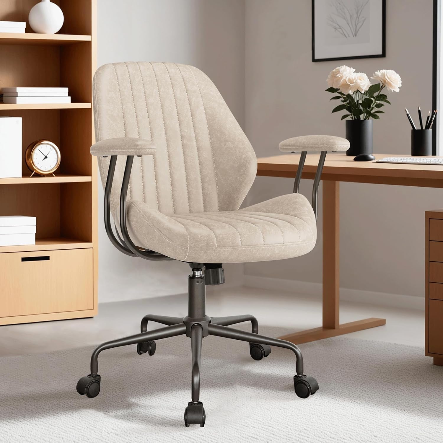 Three-quarter front view of a beige faux-suede office chair showing vertical channel stitching and rounded padded arms.