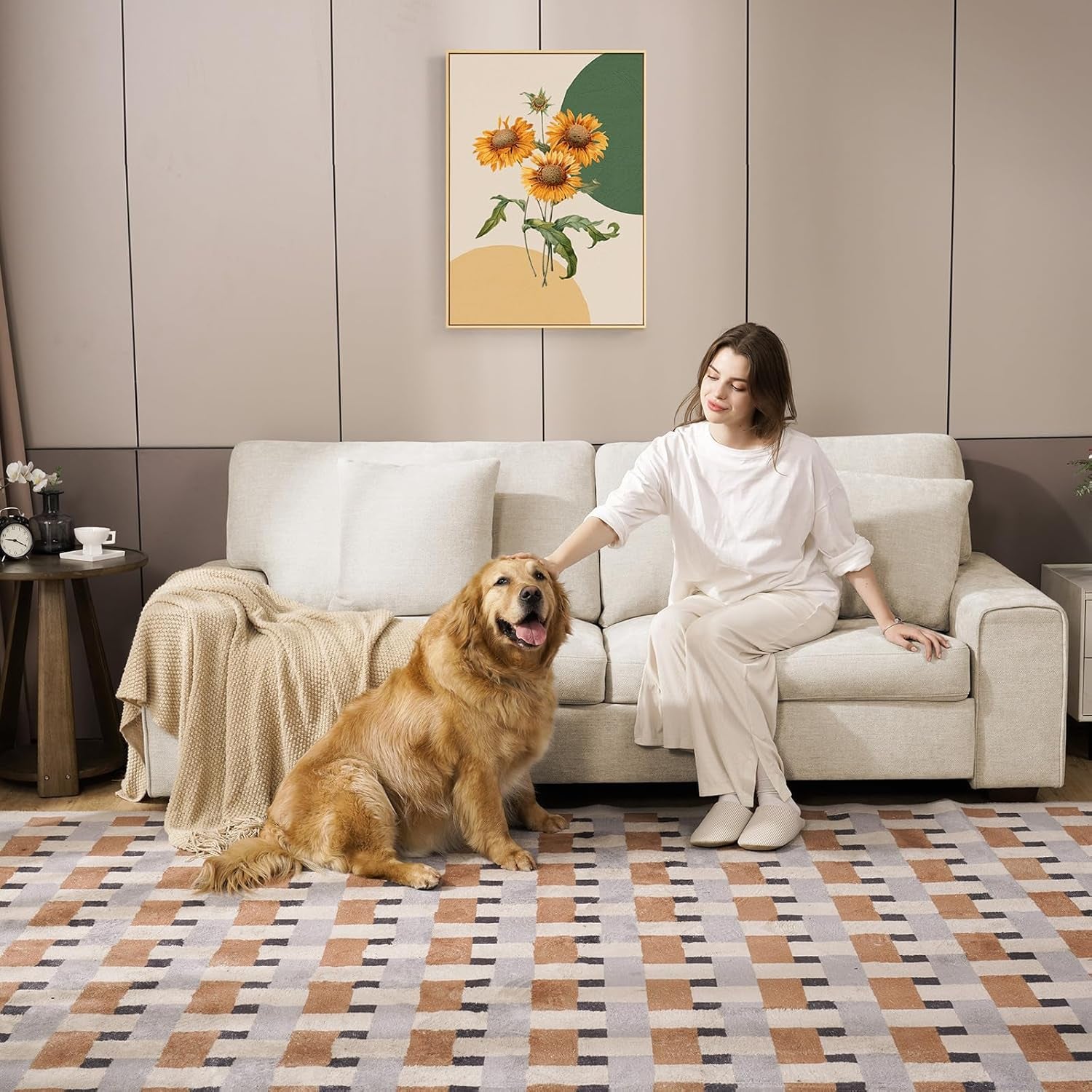 Living room scene of a woman petting a large dog while seated on the beige chenille loveseat