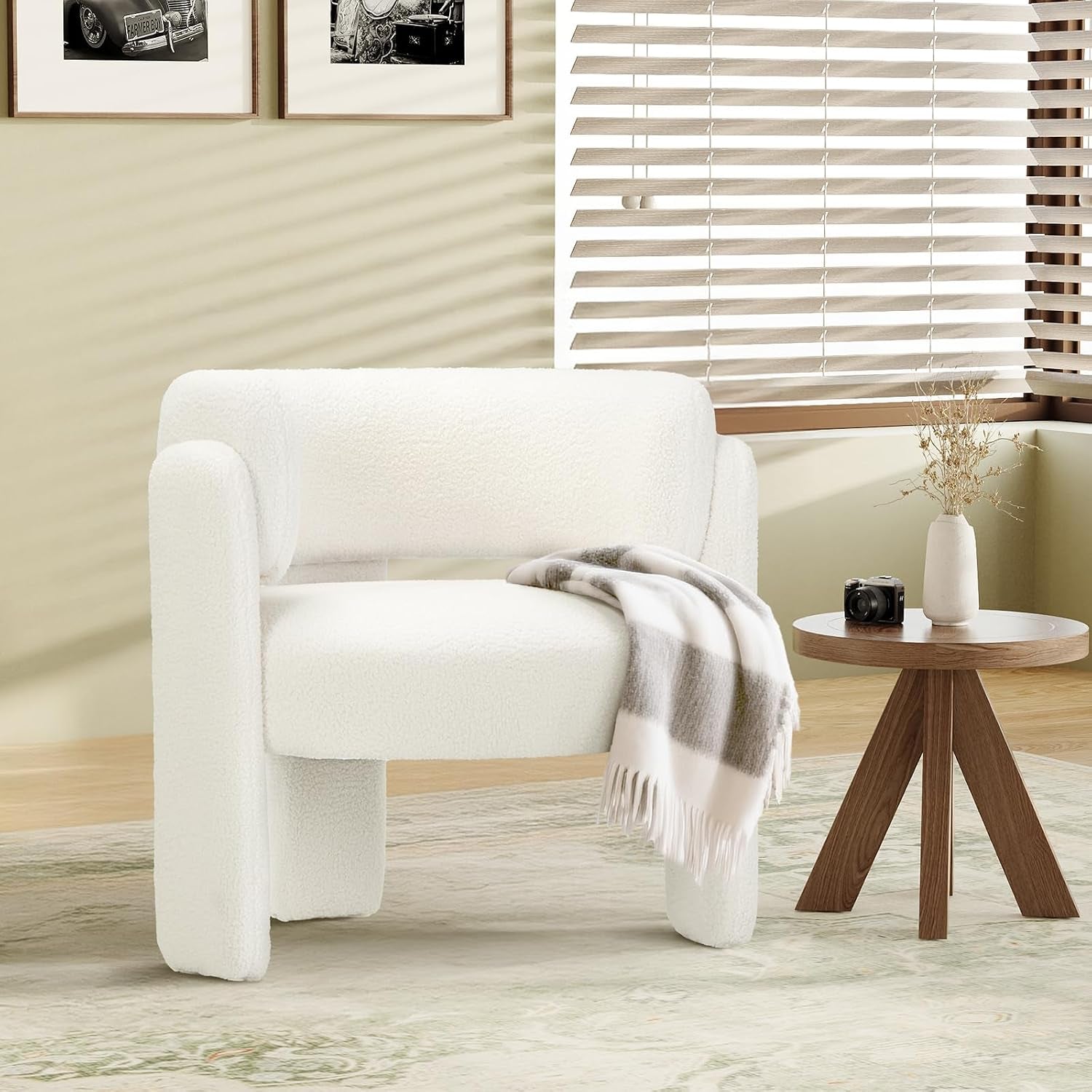 Single white sherpa barrel chair beside a round wood side table and window blinds