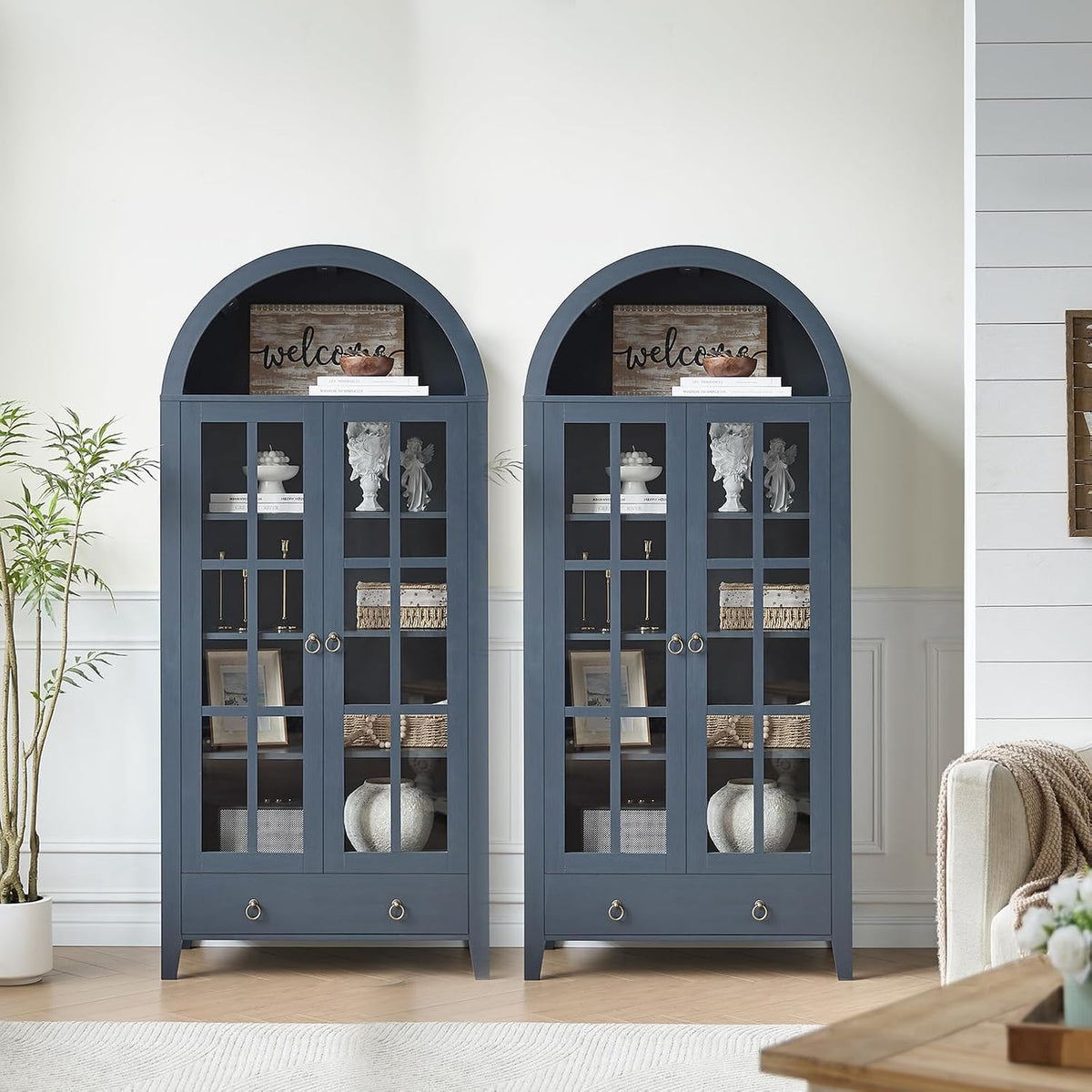 Matching pair of blue arched cabinets shown in a bright room with a sofa edge visible at right