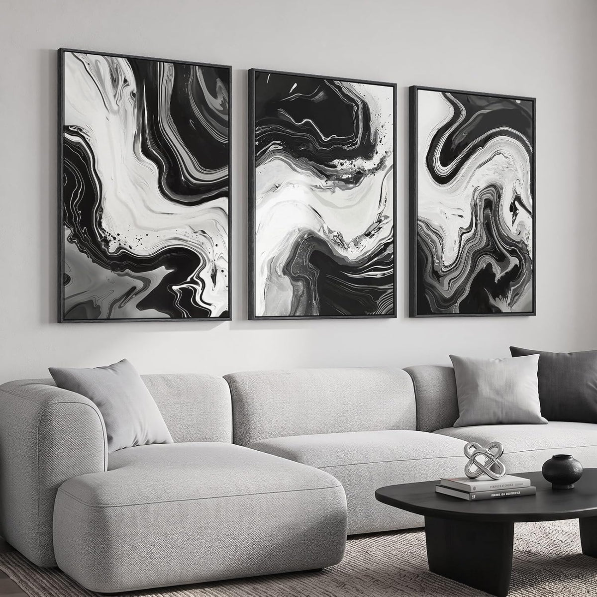 Three vertical black-and-white marbled prints with fluid swirls displayed over a light sofa.