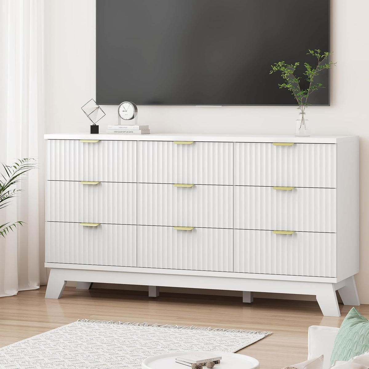 Front view of a wide white fluted dresser with gold handles beneath a wall-mounted TV in a living room.