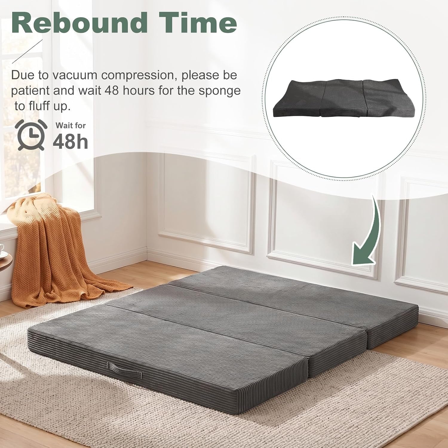 Flat dark-gray tri-fold mattress unfolded on a rug in a sunlit room, side carry handle visible.