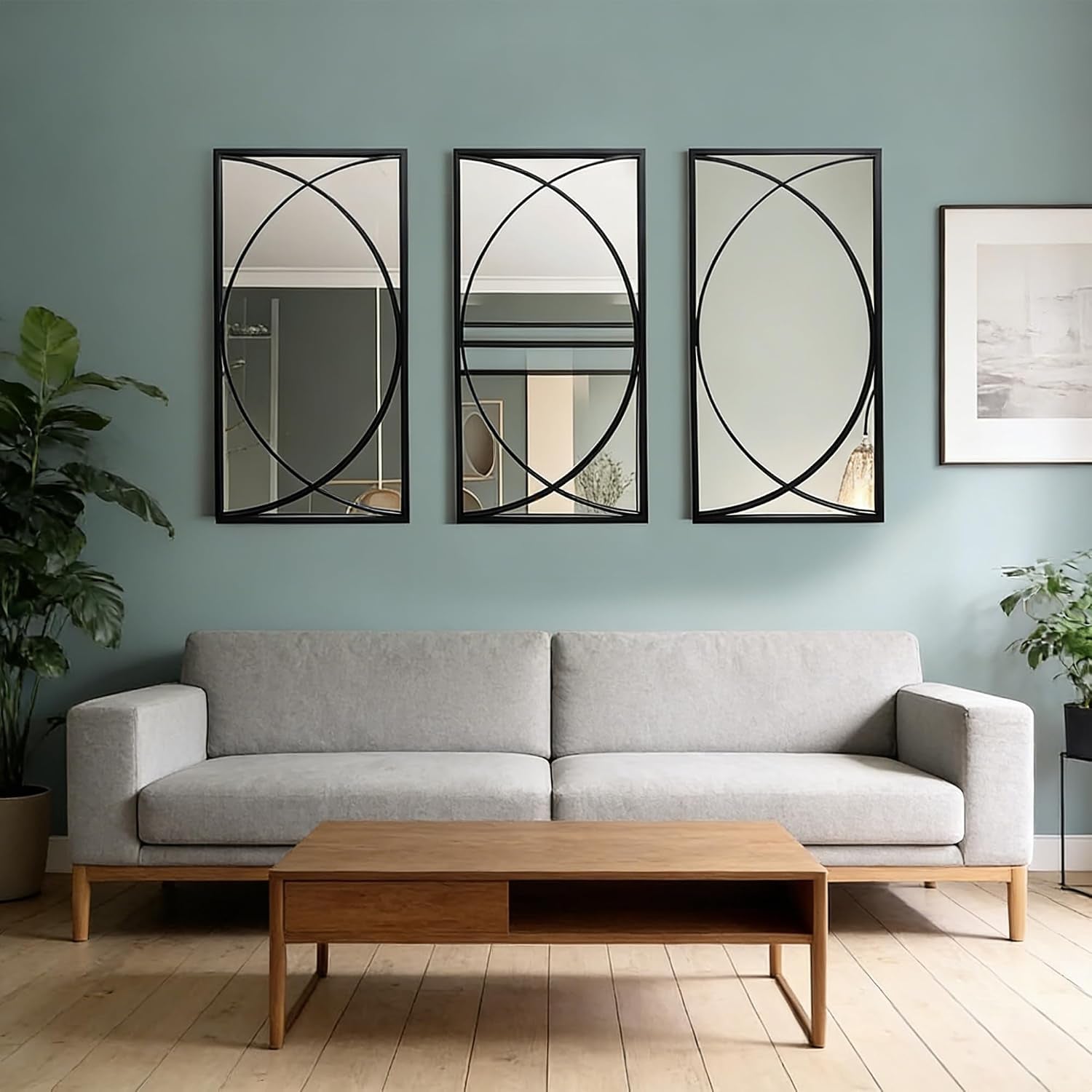 Three black rectangular mirrors with decorative circular metal accents hung above a gray sofa on a teal wall