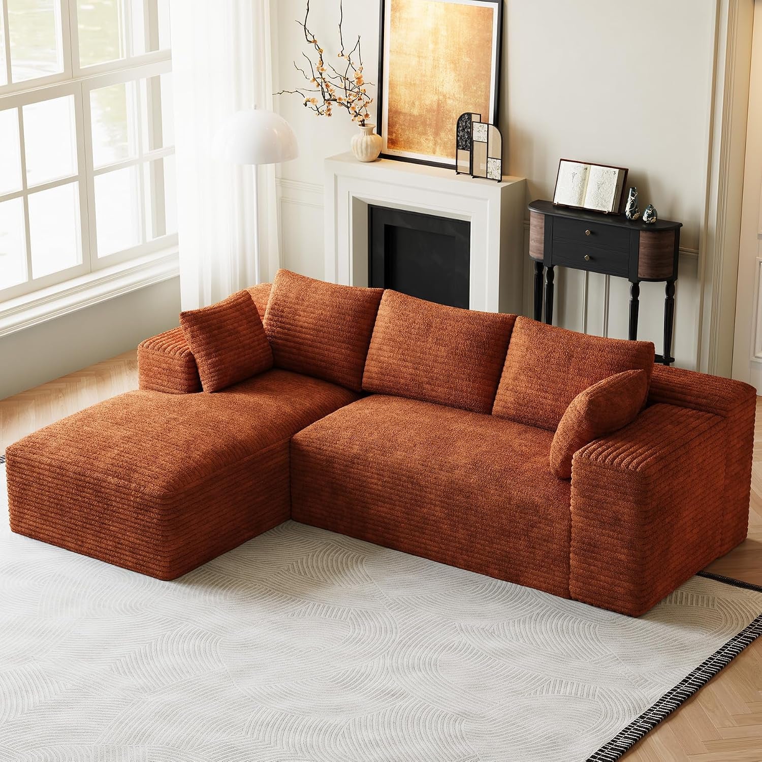 Rust-colored L-shaped modular sofa with chaise in a bright living room by a window.