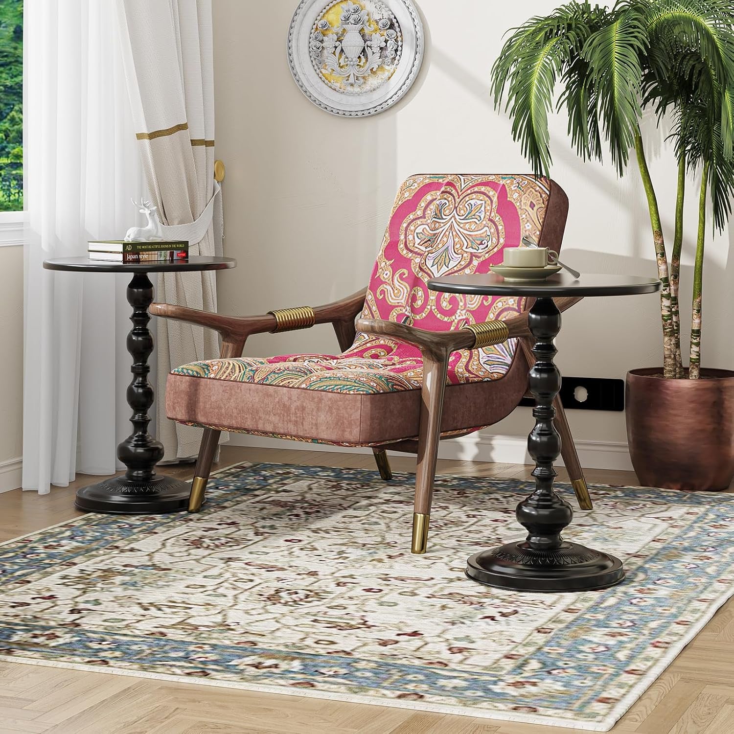 Pair of black round pedestal side tables flanking a patterned lounge chair in a sunlit room