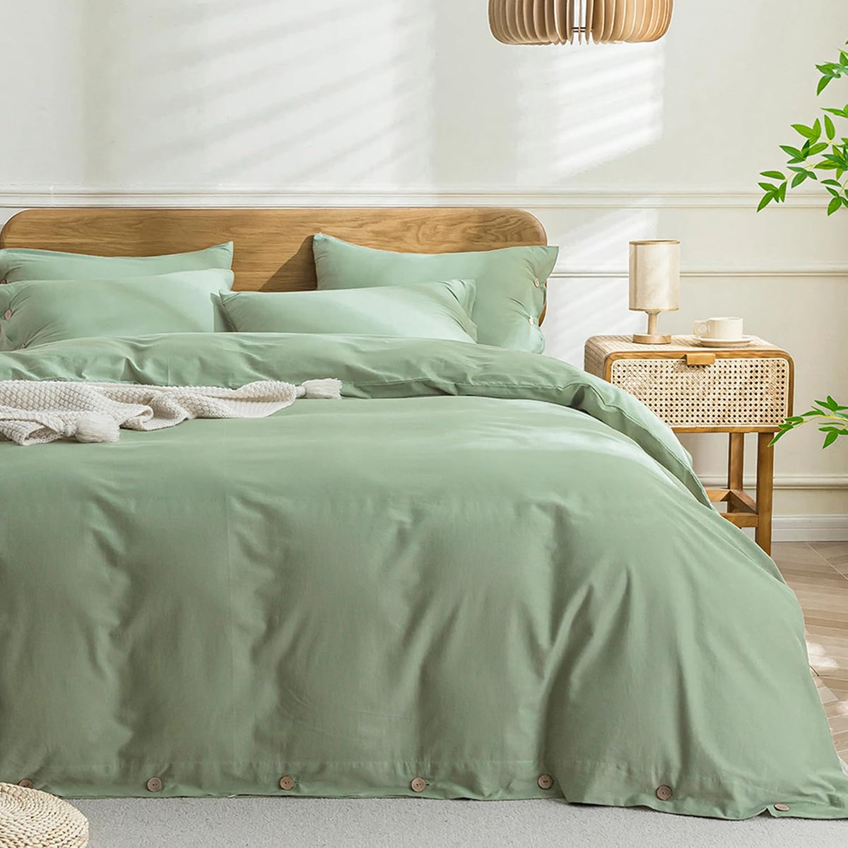 Soft mint-green duvet and matching shams on a bed, knitted throw at the foot and a cane bedside lamp at right.
