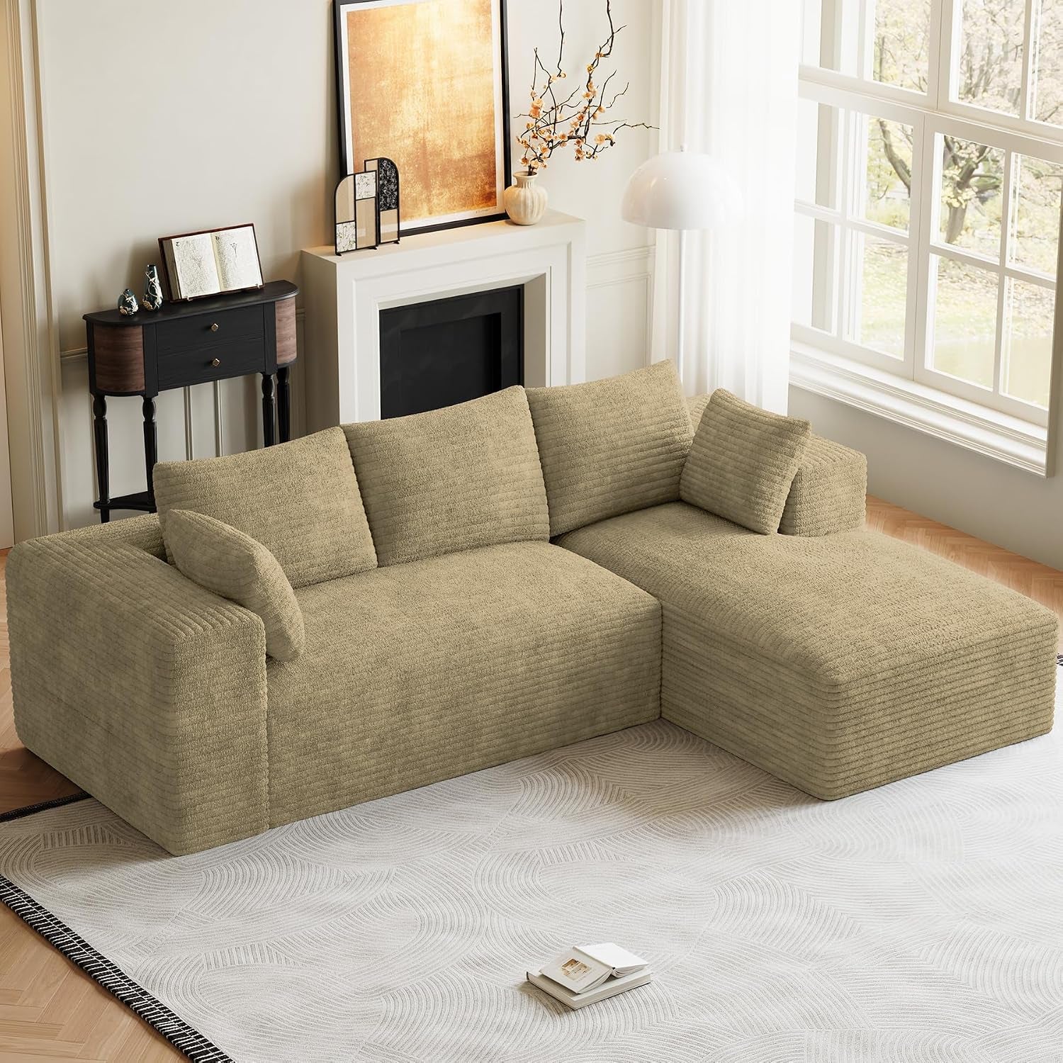Angled view of a beige L-shaped modular sectional with chaise placed on a light patterned rug.