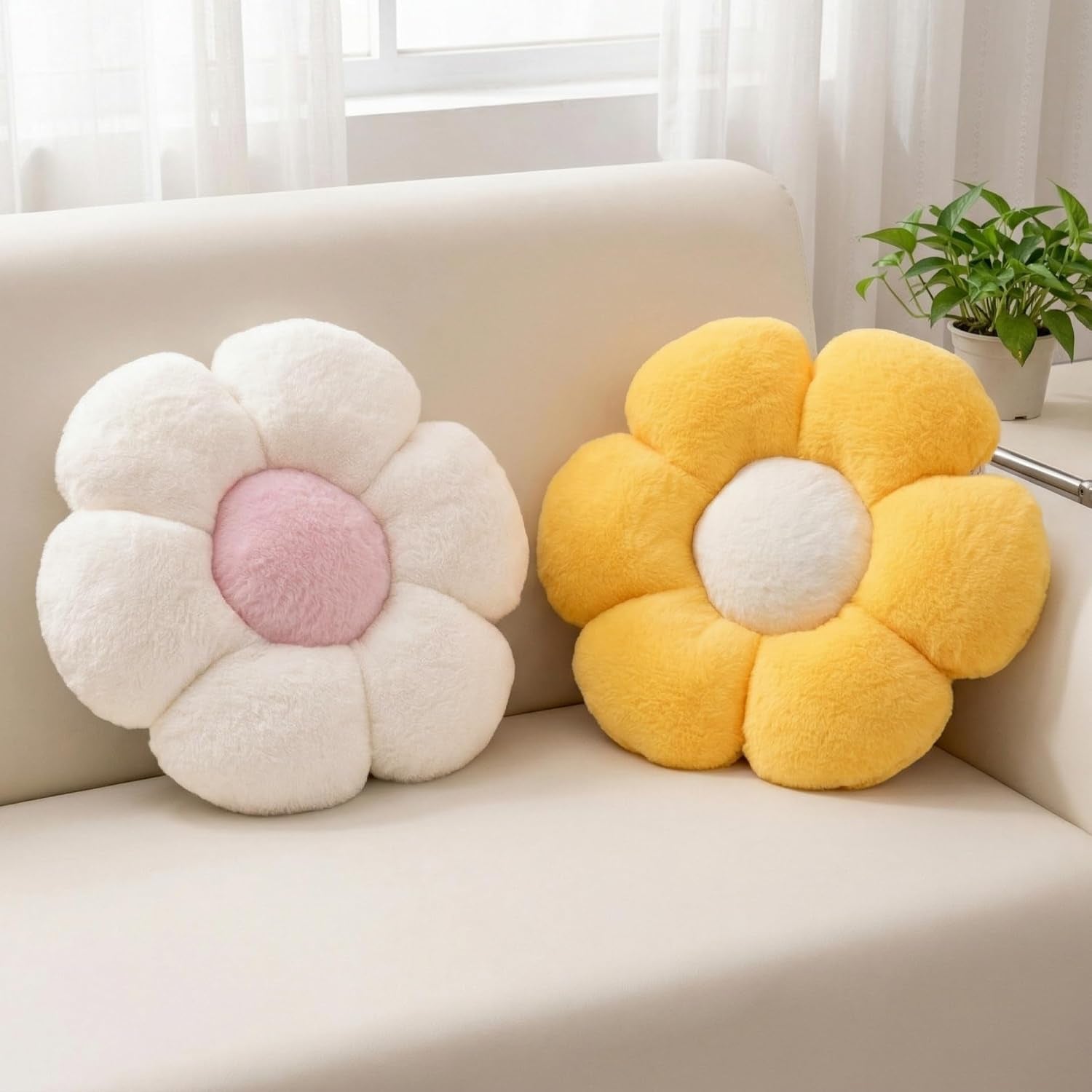 Two flower throw pillows on a cream sofa — one white with pink center, one bright yellow