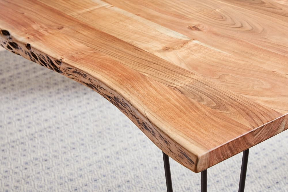 Close-up of a rounded live edge corner and gunmetal hairpin leg with visible wood texture and knots.