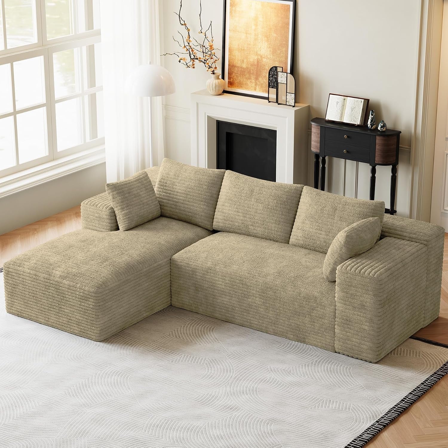 Beige L-shaped modular sectional with left chaise in a bright living room by a window.
