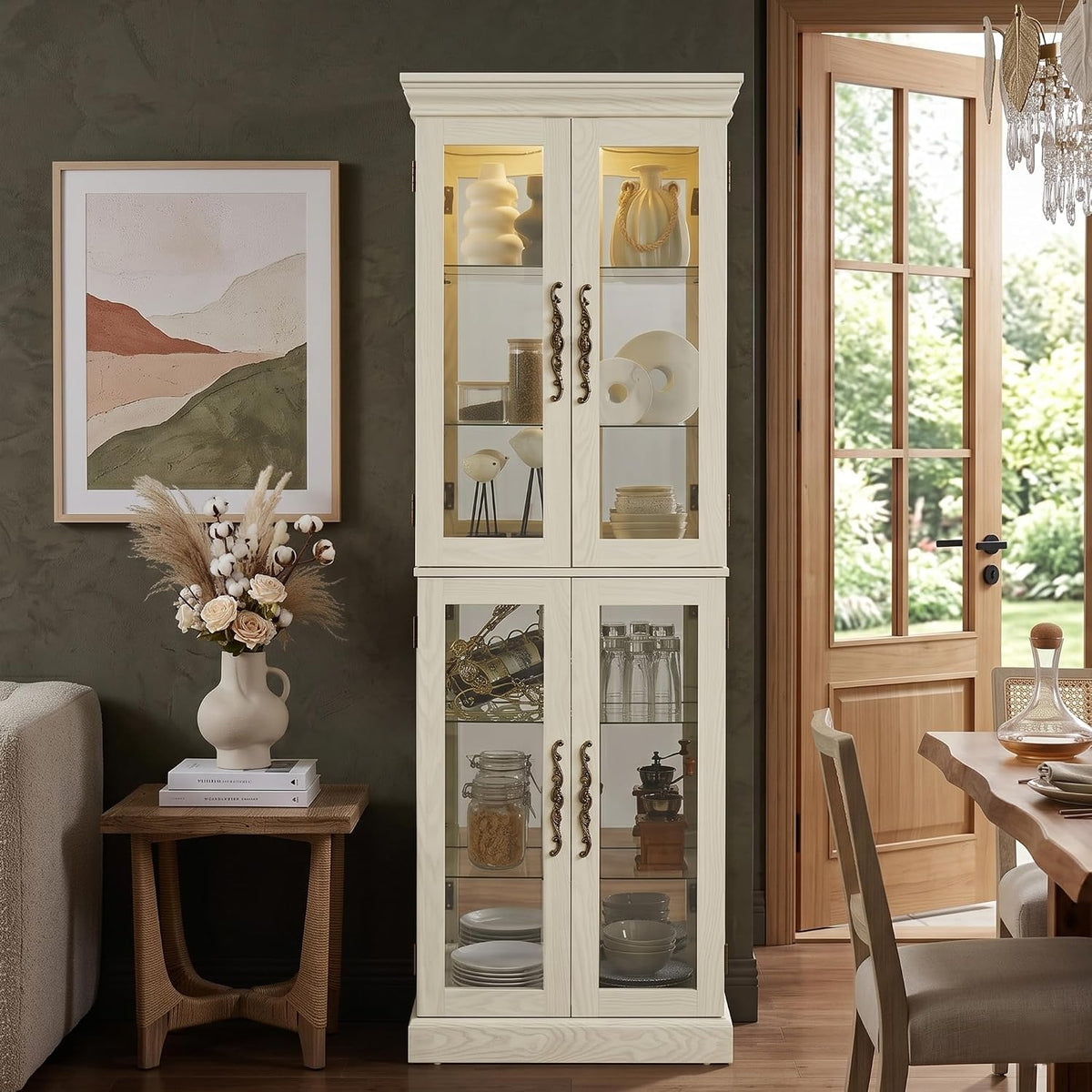 White lighted tall curio cabinet with glass doors staged in a dining room next to framed art and a side table