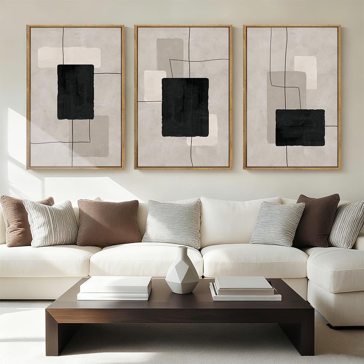 Living room view showing three framed abstract compositions with black blocks and thin line accents over the sofa.