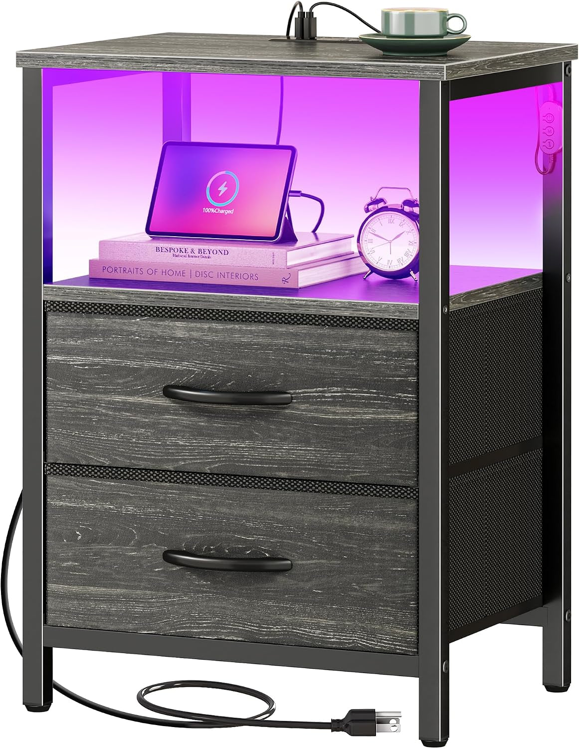 Nightstand with dark-gray wood drawers, illuminated open shelf with tablet and alarm clock, top outlet visible.
