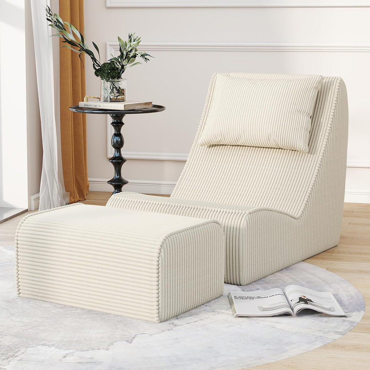 Cream-colored chaise lounge and ottoman angled slightly right beside a round side table and open magazine.