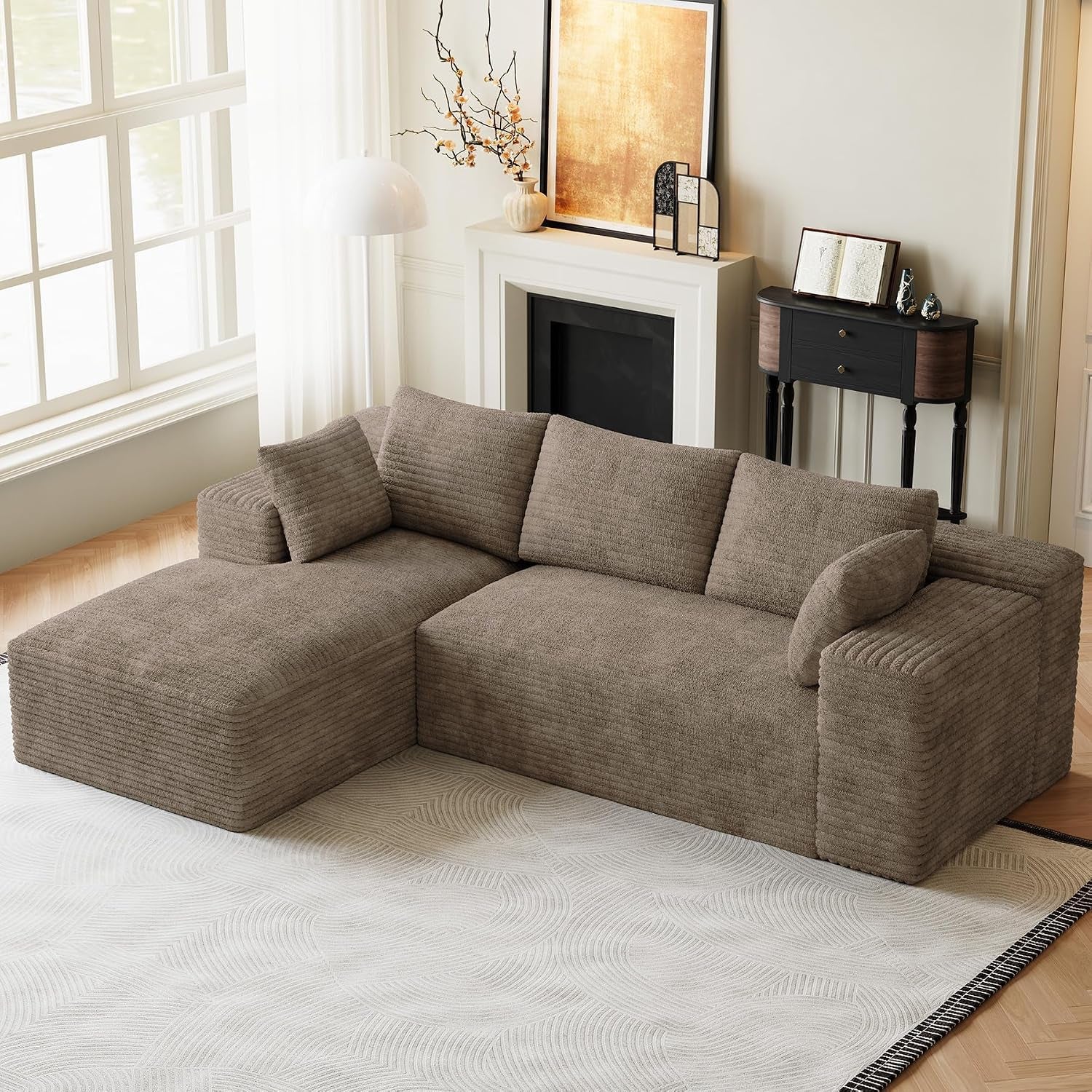 Angled front view of a brown/taupe modular sectional with chaise placed on a pale patterned rug