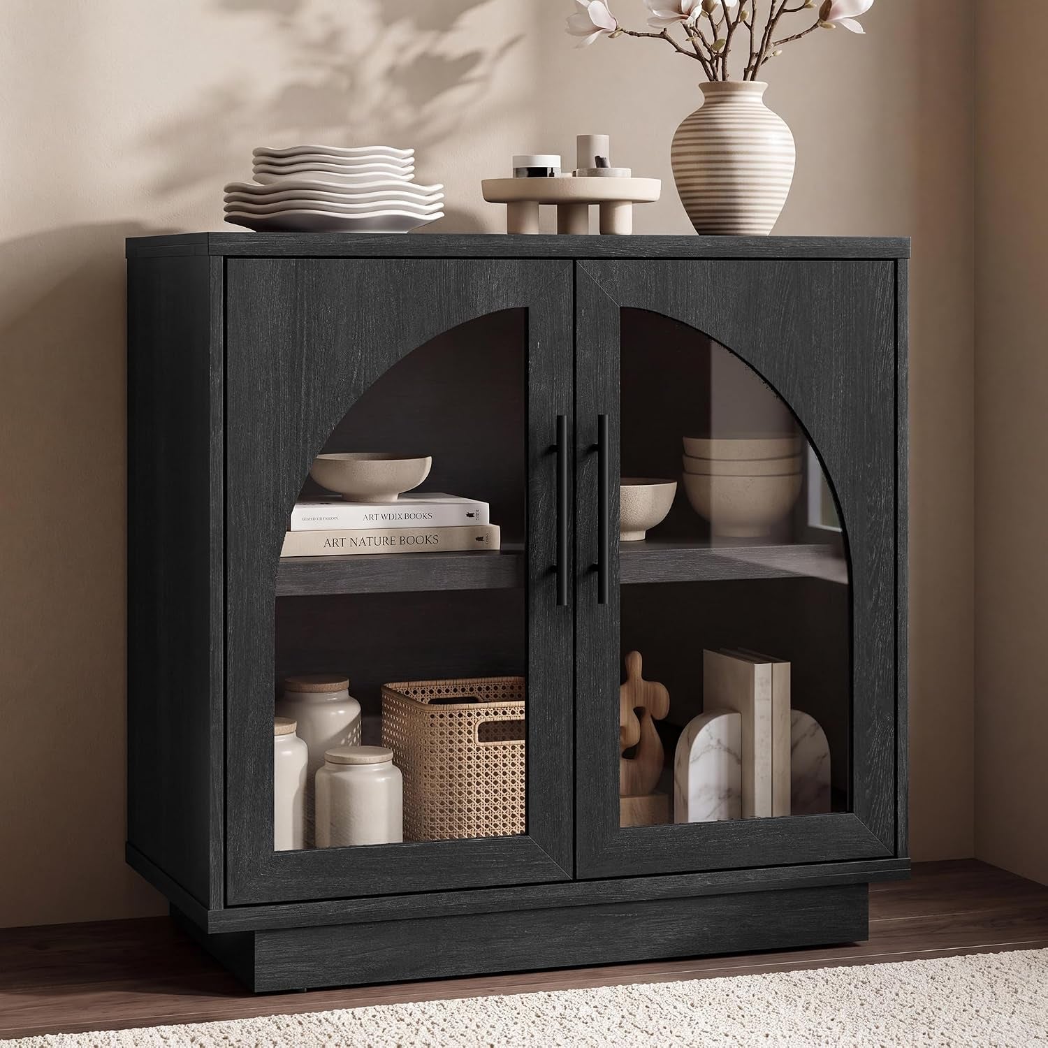 Close-up of a black cabinet with arched glass doors showing interior shelves with dishes and decor