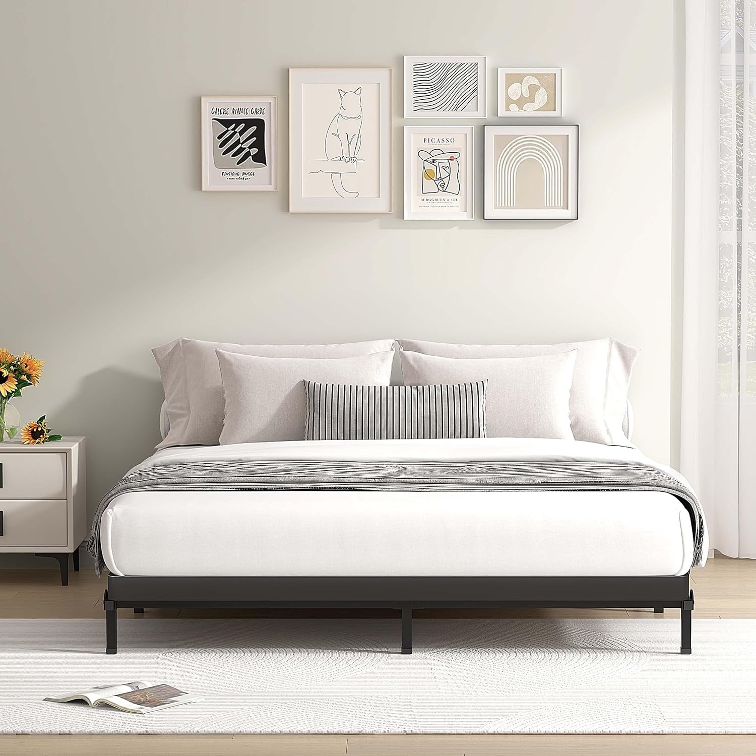 Front-facing shot of a minimalist black metal bed base supporting a mattress in a bright bedroom