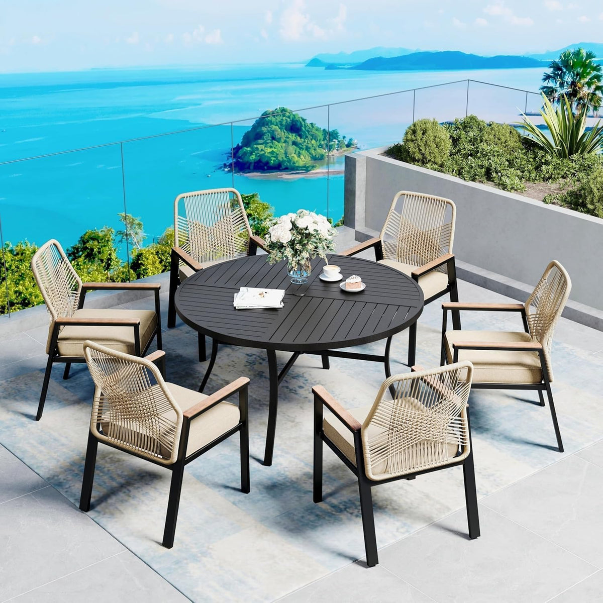 Outdoor terrace setting featuring the round metal dining table surrounded by six woven armchairs with ocean view