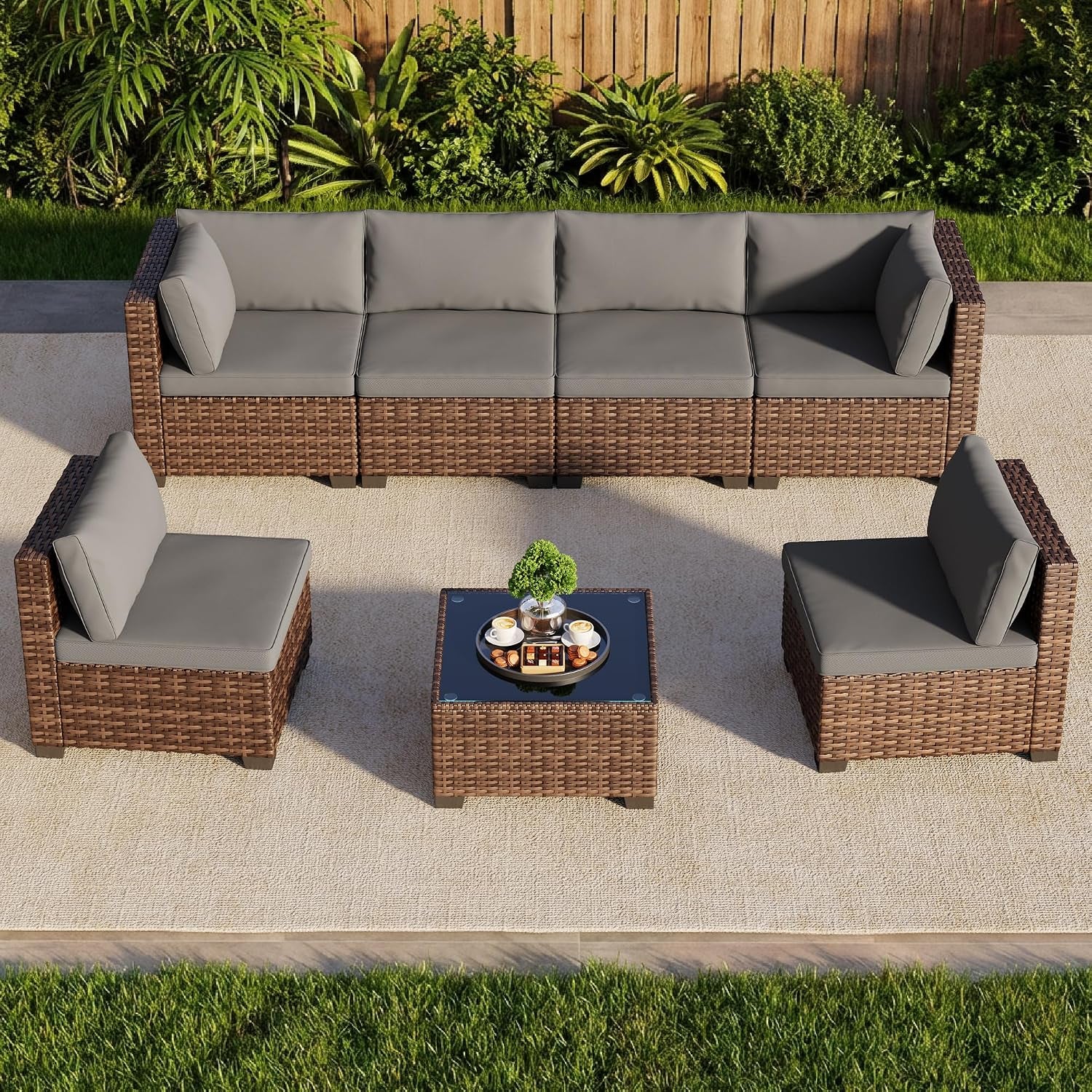 Overhead view of the rattan sectional and two armless chairs flanking a glass-top coffee table on an outdoor rug.
