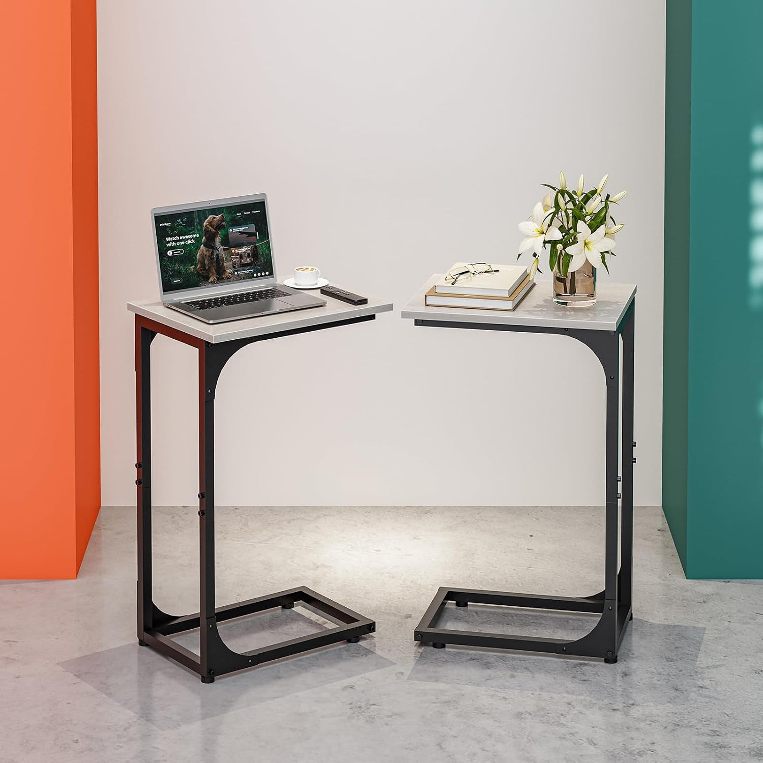 Two C-shaped end tables facing each other with light gray tops, one with a laptop and the other with books and a vase of