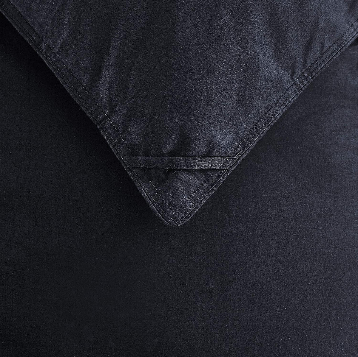 Close-up of a black comforter corner showing stitched seam and a corner loop detail for duvet attachment