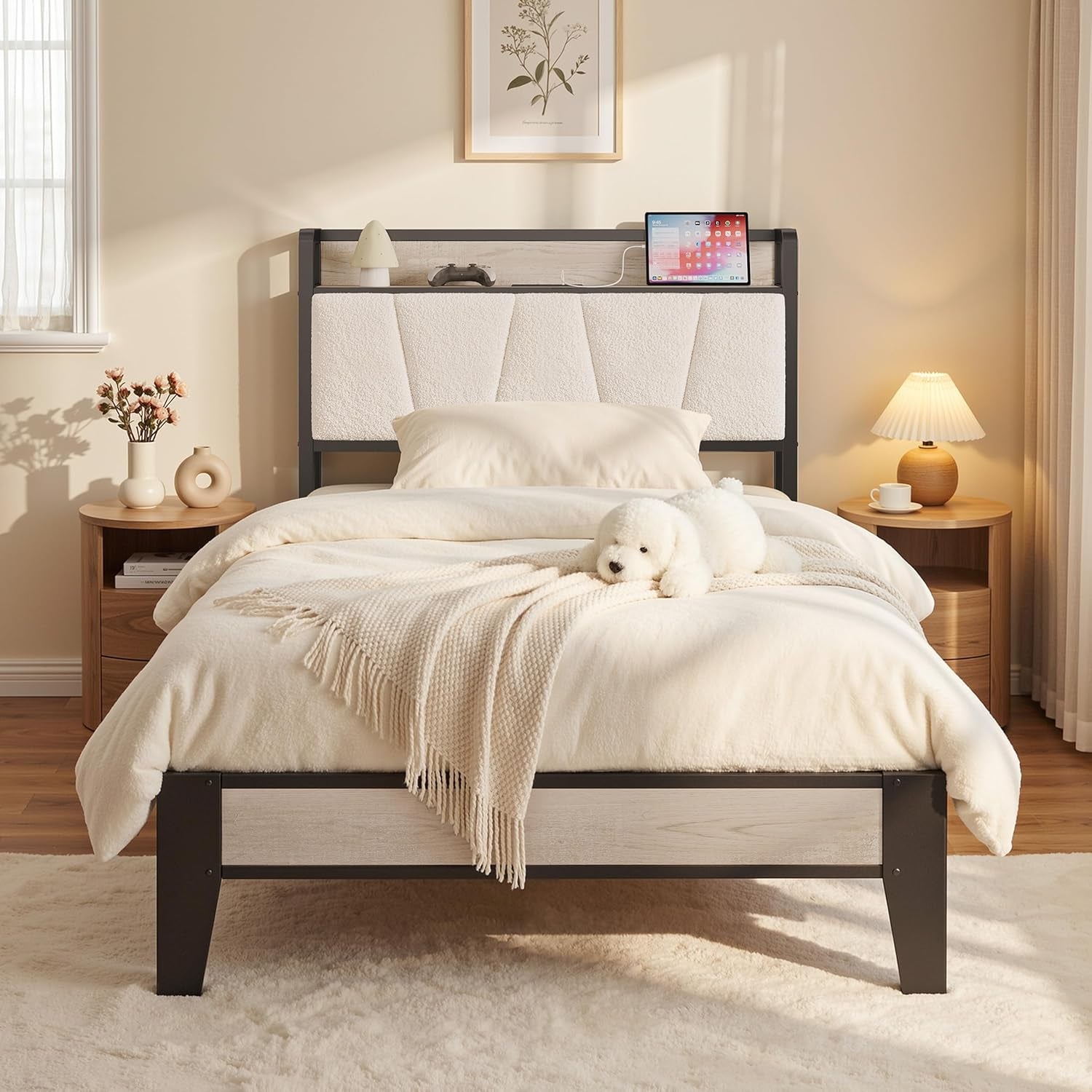 Front-facing image of a bed with cream bedding, cushioned headboard panels, and black metal legs framing a pale wood