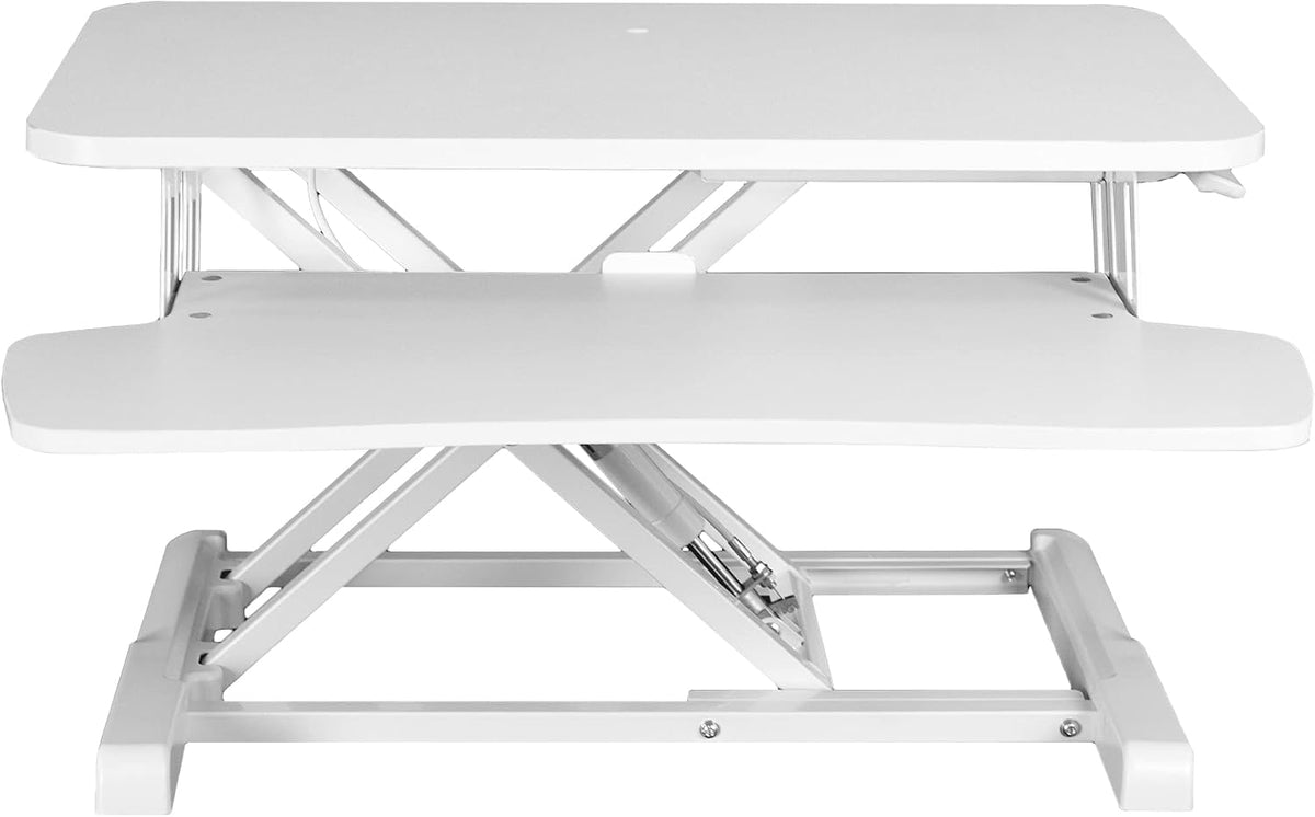 Front view of white standing desk converter showing scissor-lift frame and keyboard tray