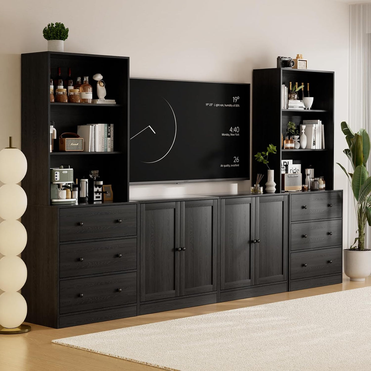 Black-finish modular TV stand with matching tall bookcases flanking a wall-mounted TV, styled with books and decor.
