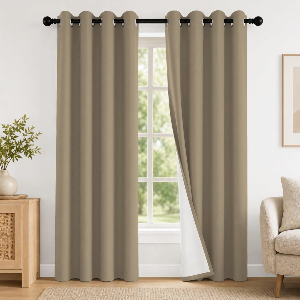 Front view of taupe grommet curtains, one panel drawn aside showing white lining, with nearby console and beige armchair.