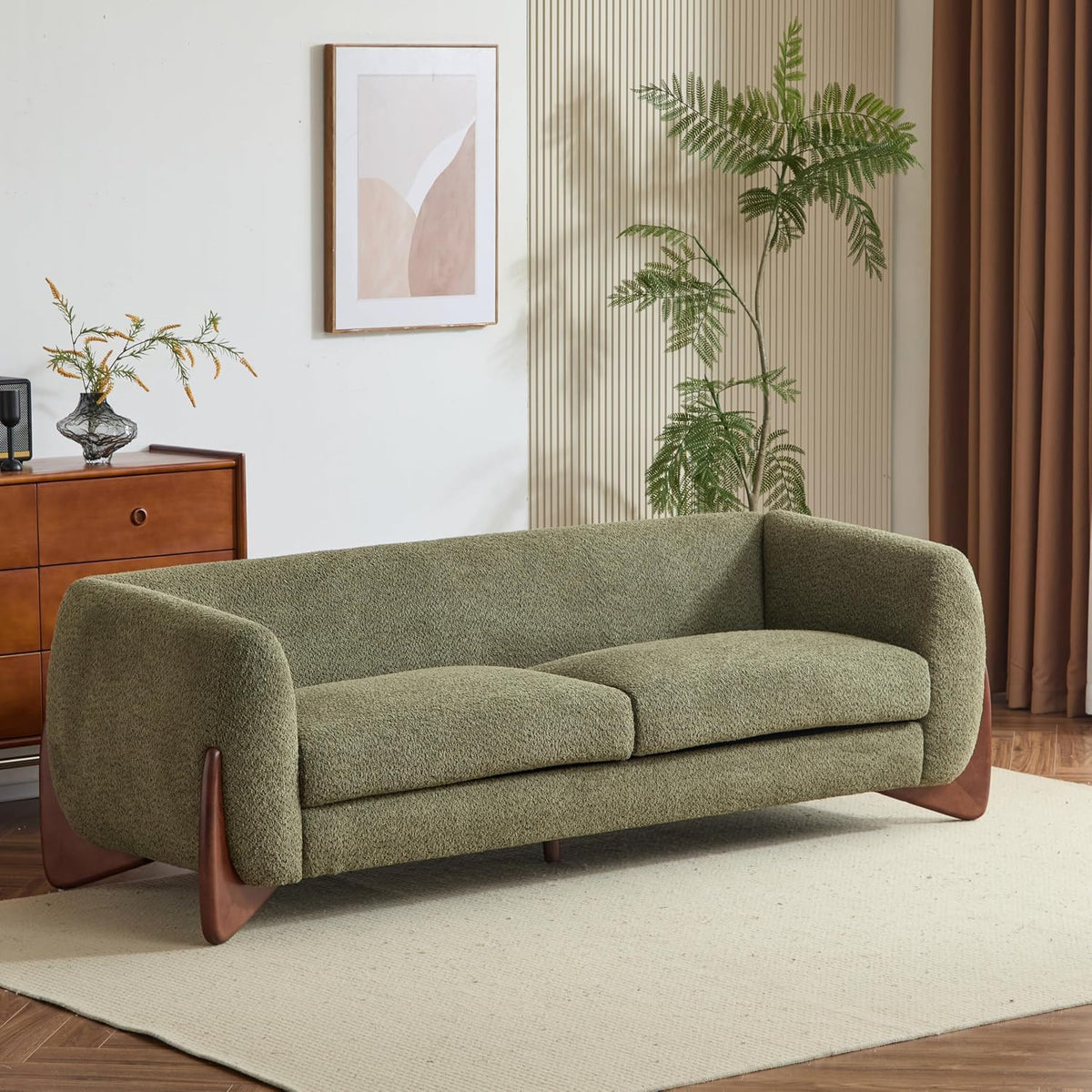 Olive-green boucle three-seat sofa with curved arms and wooden triangle legs in a styled living room.