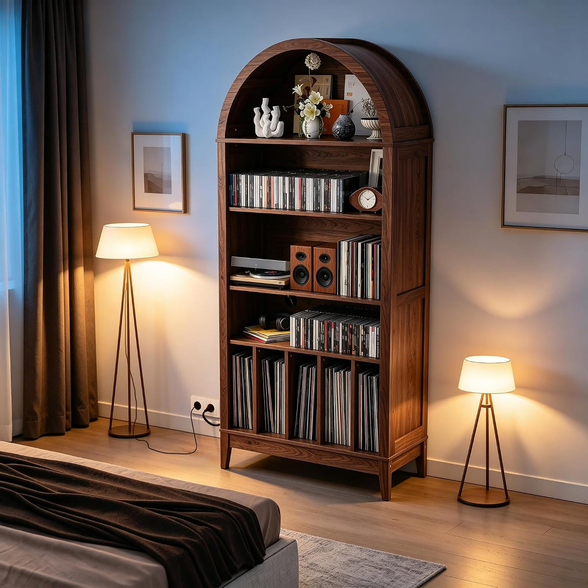 Tall arched walnut record cabinet filled with vinyl, speakers and decor between two floor lamps in a bedroom