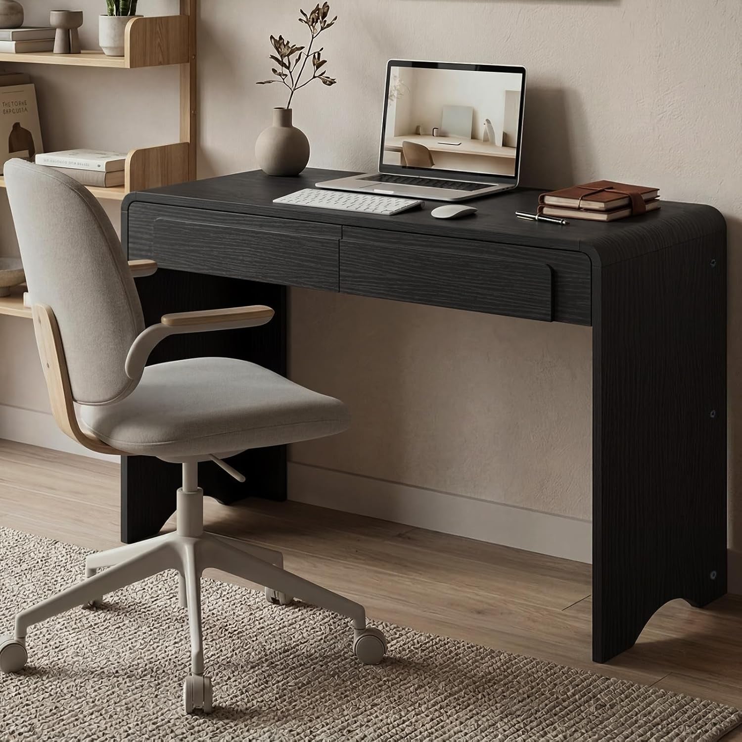 Angled close view of the black desk showing the slim top drawers, keyboard, and arched leg detail