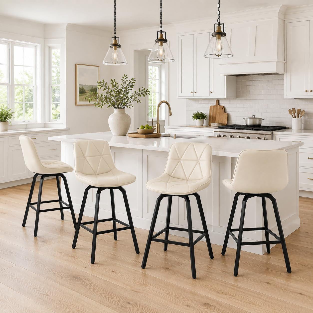 Four cream-colored faux-leather counter stools with black metal frames lined up at a white kitchen island under pendant