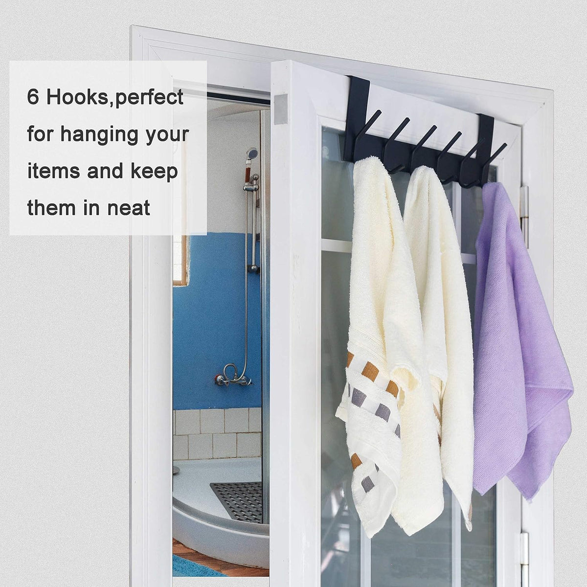 Black over-the-door rack hung on a white door holding two cream towels and a purple towel