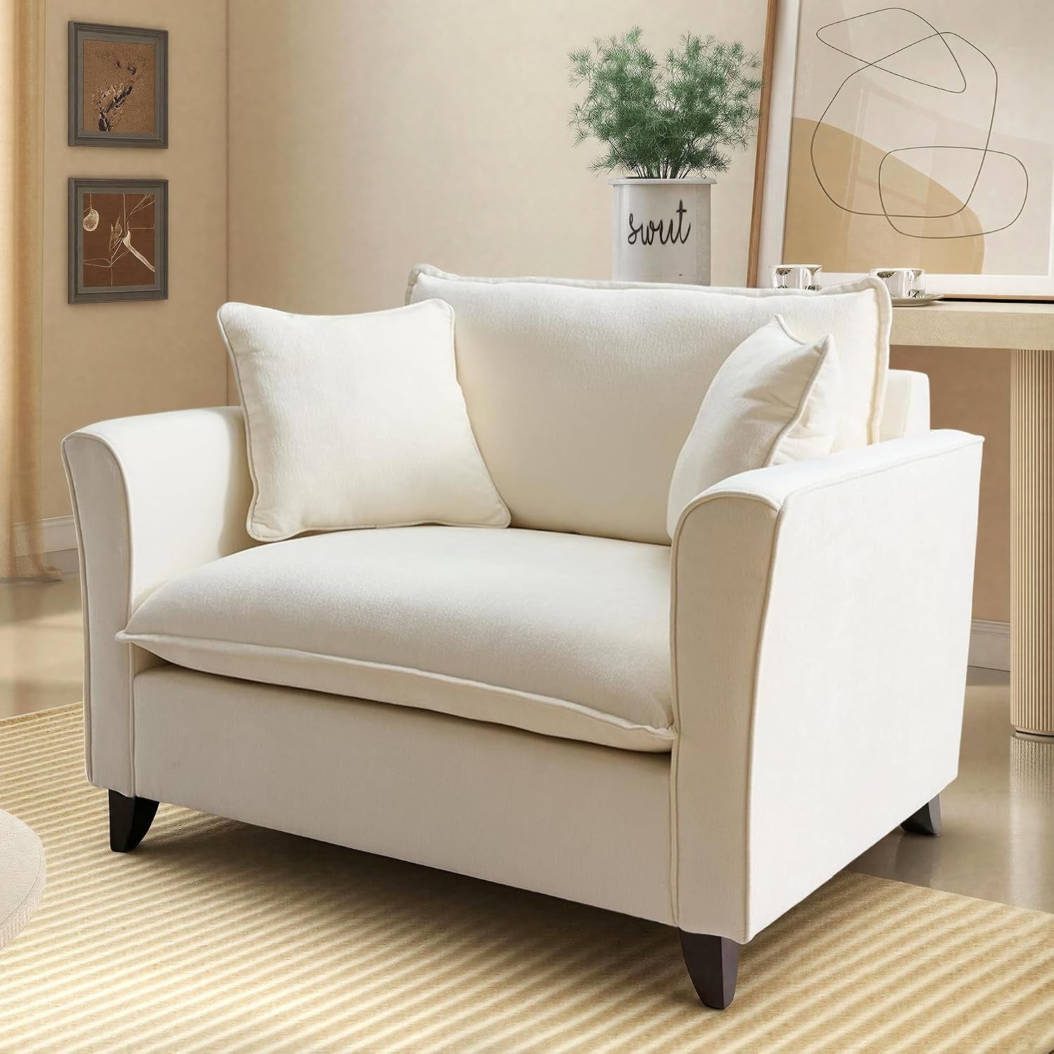 Angled front-right view of an oversized cream chenille accent chair with two square throw pillows in a staged room.