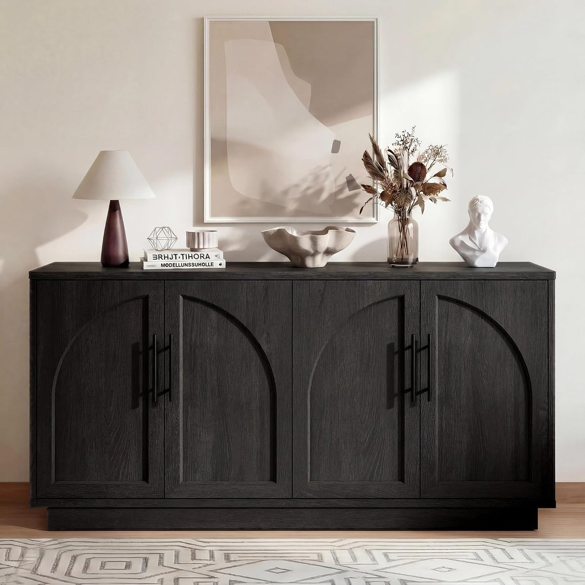 Dark wood buffet with four arched doors and black handles, styled with a lamp, bowl, vase and framed art above.