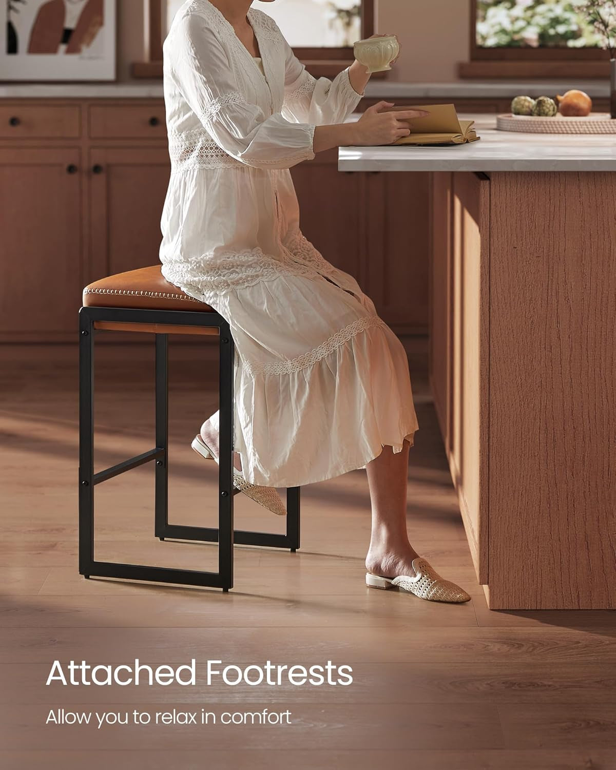 Woman in a white dress seated on a stool at the counter, reading and holding a cup, showing the attached footrest.