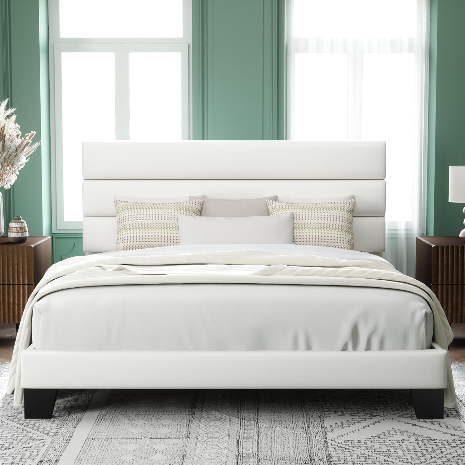 Centered bedroom view of a white upholstered bed against green walls with dark feet.