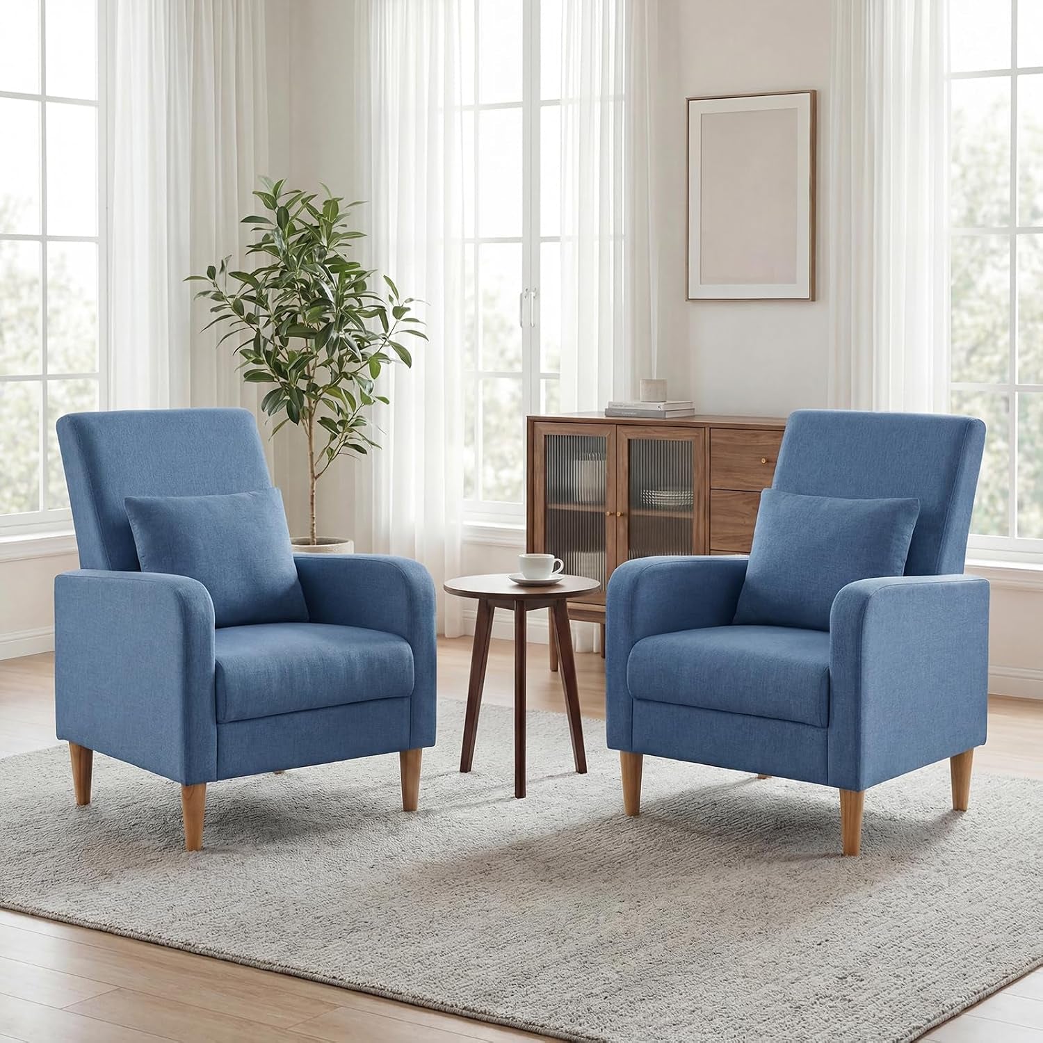 Pair of medium blue upholstered accent chairs facing each other with small round table between