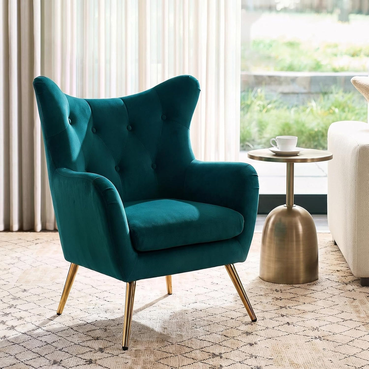 Close side view of a single teal wingback chair with gold-tone round side table and teacup.